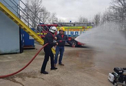 A firefighter spraying water on a fire truck Description automatically generated