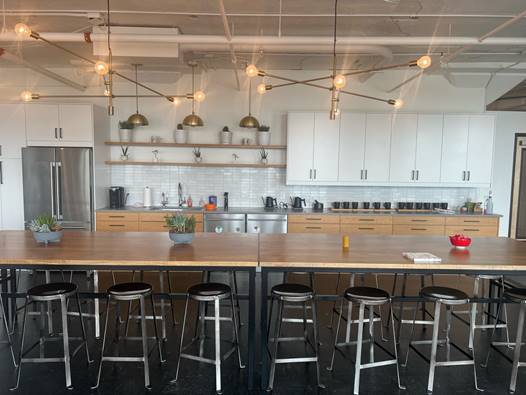 A long table with stools in a room with white cabinets

Description automatically generated