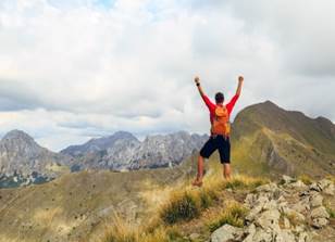 A person standing on a mountain with his arms raised

Description automatically generated